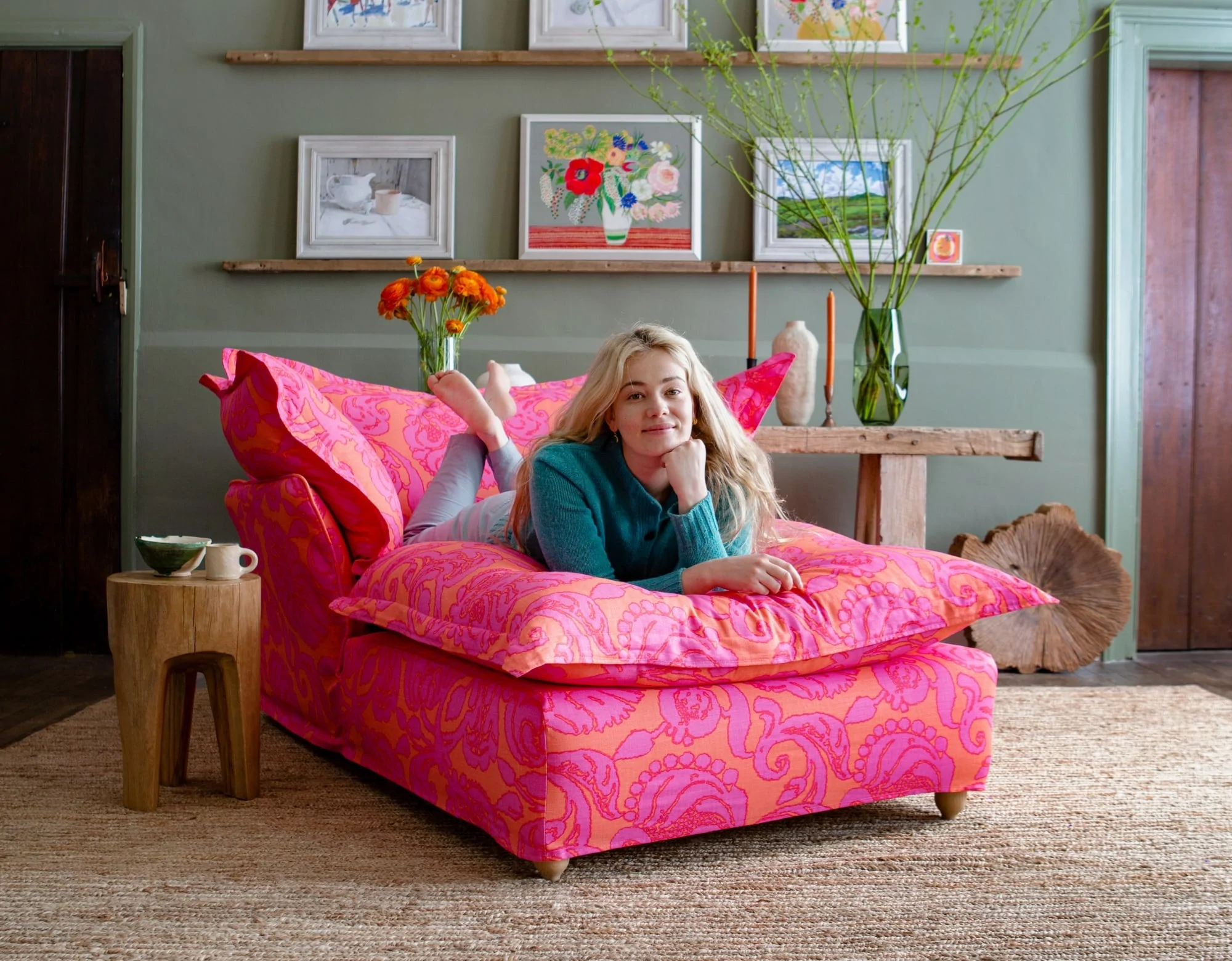 Marnie laying on a Maker and Son Song pillow edge Armchair Chaise in Christopher Farr bespoke pink and orange Anna print.