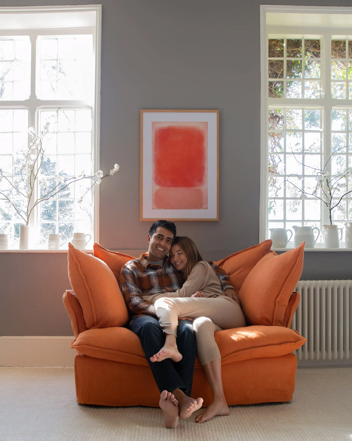Couple snuggled up on a Maker and Son Loveseat in orange linen.
